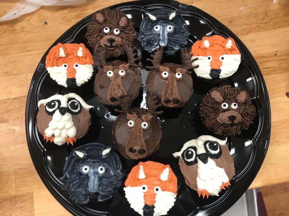 A platter of cupcakes decorated like foxes, bears, moose and owls